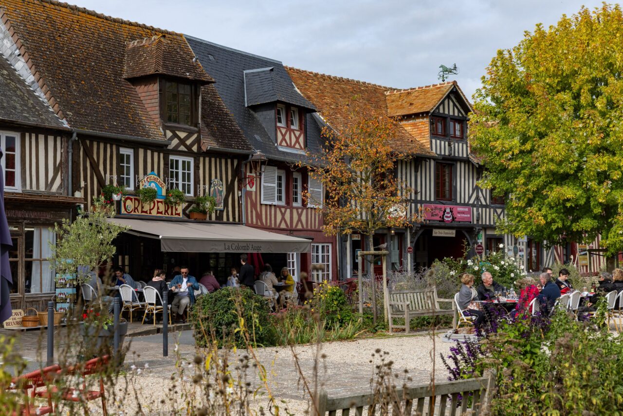Dorfplatz von Beuvron-en-Auge mit Fachwerkhäusern und Café im Herbst
